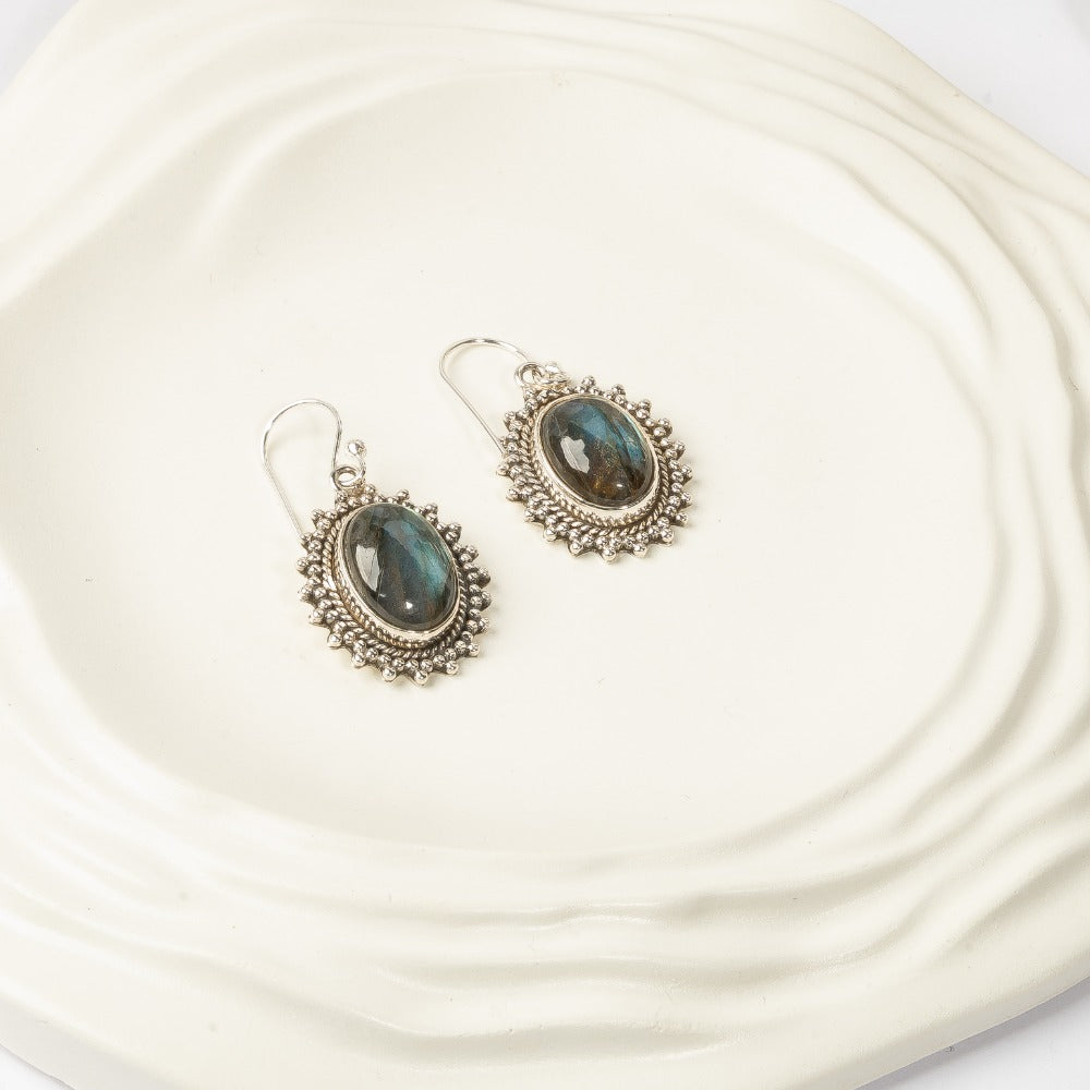 Pair of silver earrings with gemstones on a textured white surface
